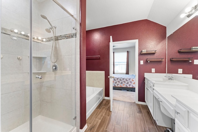 bathroom featuring wood finish floors, lofted ceiling, a shower stall, ensuite bath, and vanity