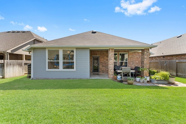 back of house featuring a yard, a fenced backyard, brick siding, and a patio