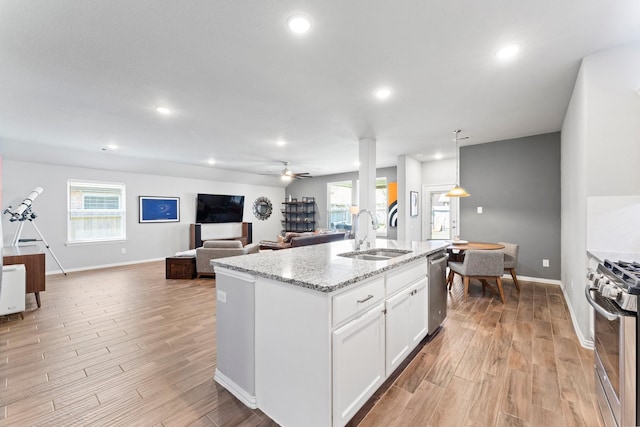 kitchen featuring appliances with stainless steel finishes, a center island with sink, a sink, and light wood-style flooring