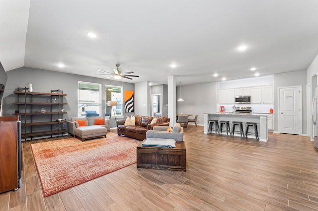 living area featuring baseboards, light wood-type flooring, a ceiling fan, and recessed lighting