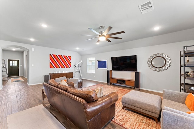 living room with arched walkways, visible vents, a ceiling fan, wood finished floors, and baseboards