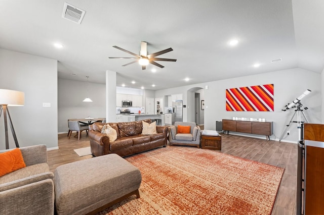 living area featuring visible vents, arched walkways, lofted ceiling, ceiling fan, and wood finished floors