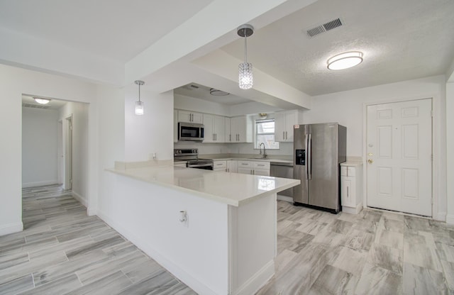 kitchen featuring a peninsula, a sink, visible vents, light countertops, and appliances with stainless steel finishes