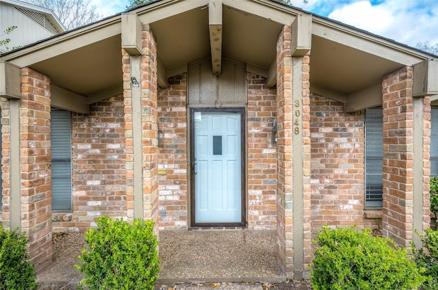 view of exterior entry featuring brick siding