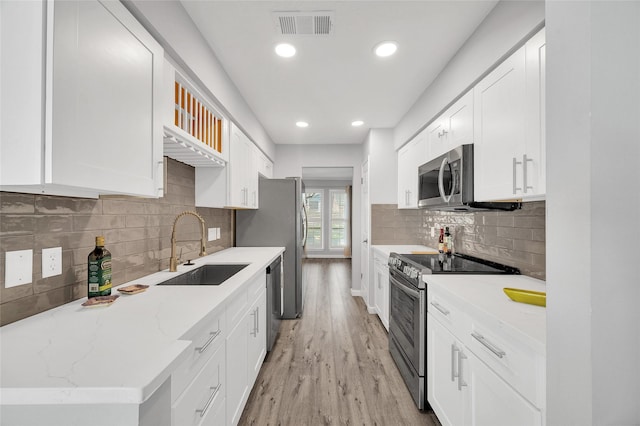 kitchen with visible vents, appliances with stainless steel finishes, light wood-style floors, white cabinets, and a sink