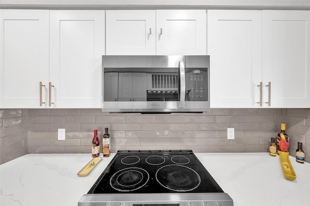 3048 Gessner Rd, Houston, TX 77080 - kitchen with stainless steel microwave, white cabinetry, stove, and decorative backsplash