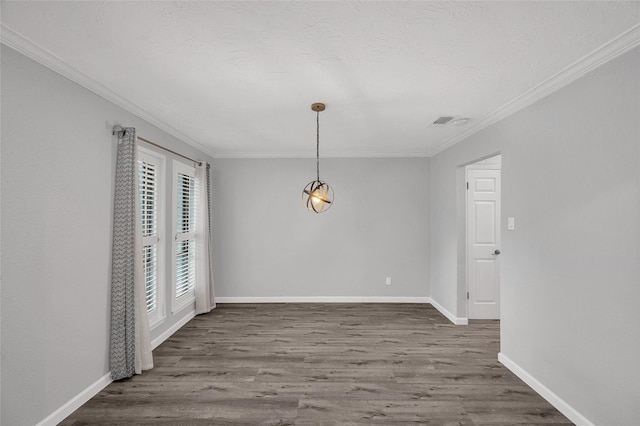 unfurnished dining area featuring baseboards, a textured ceiling, ornamental molding, and wood finished floors