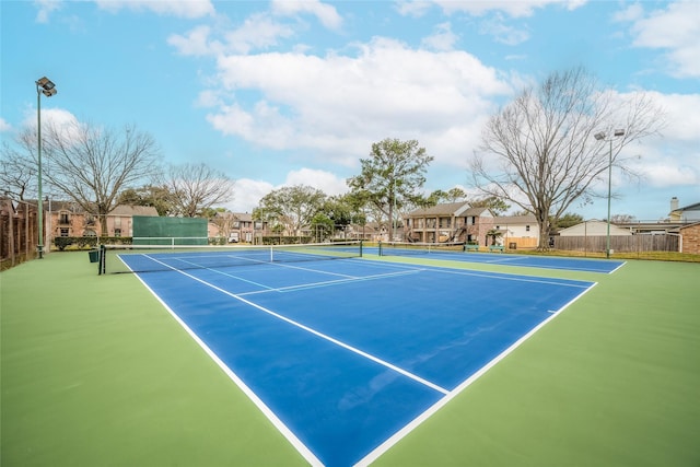 view of tennis court with a residential view and fence