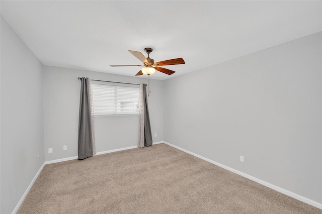 spare room with a ceiling fan, light carpet, and baseboards