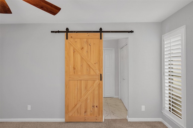 spare room with light carpet, a barn door, and baseboards