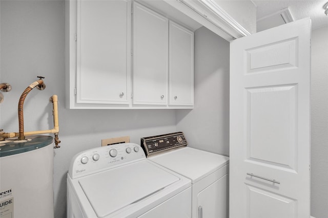 washroom featuring water heater, washing machine and clothes dryer, and cabinet space