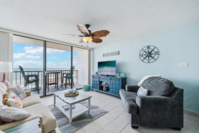 tiled living area featuring a ceiling fan, expansive windows, and a textured ceiling