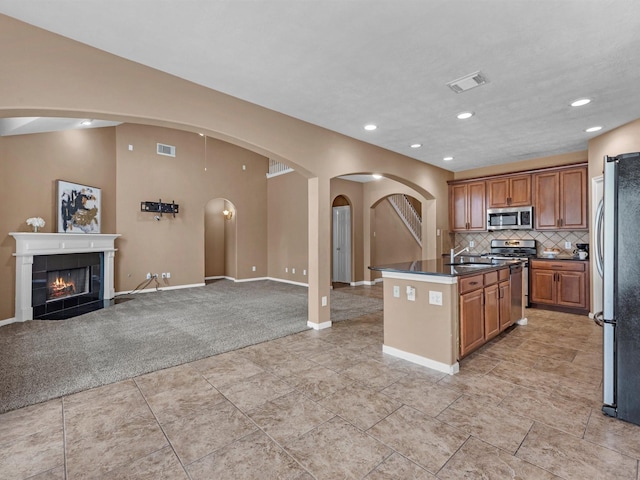 kitchen featuring brown cabinets, dark countertops, visible vents, appliances with stainless steel finishes, and a tile fireplace