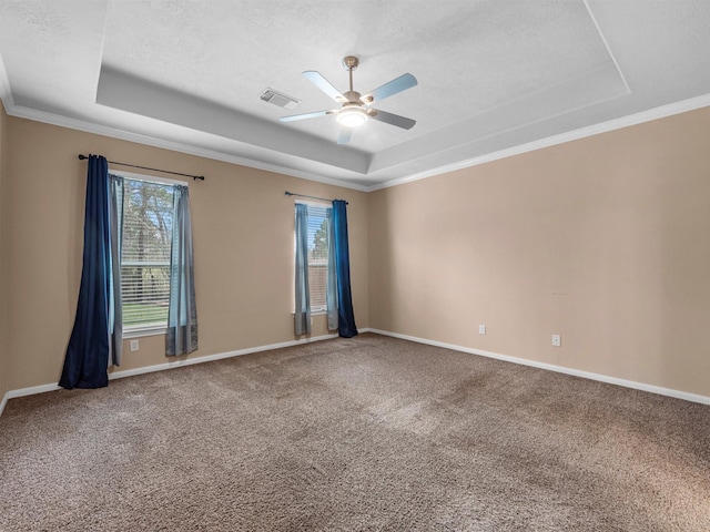 carpeted spare room with a tray ceiling, ceiling fan, and baseboards