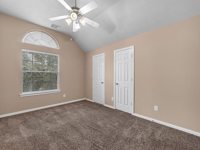 unfurnished bedroom featuring baseboards, visible vents, ceiling fan, vaulted ceiling, and carpet flooring