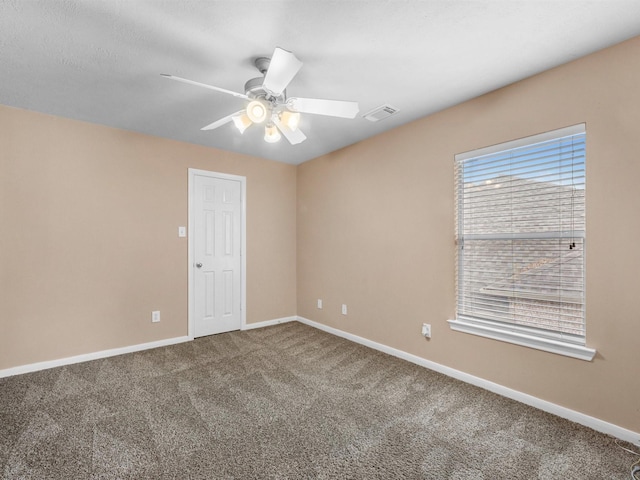 spare room featuring carpet floors, visible vents, baseboards, and a ceiling fan