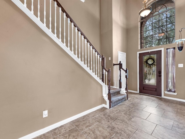 foyer entrance featuring stairs, a high ceiling, and baseboards