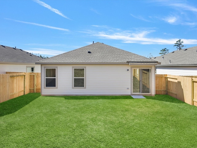 back of property with a fenced backyard, a lawn, and roof with shingles