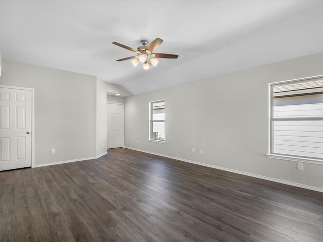 empty room featuring dark wood-style floors, lofted ceiling, and baseboards