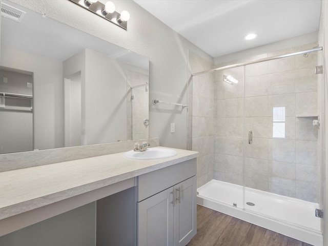 bathroom with a stall shower, visible vents, vanity, and wood finished floors