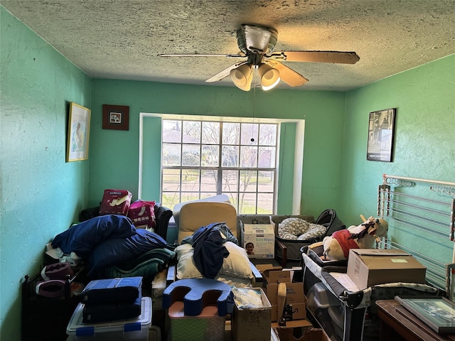 bedroom featuring a textured ceiling, a textured wall, and a ceiling fan