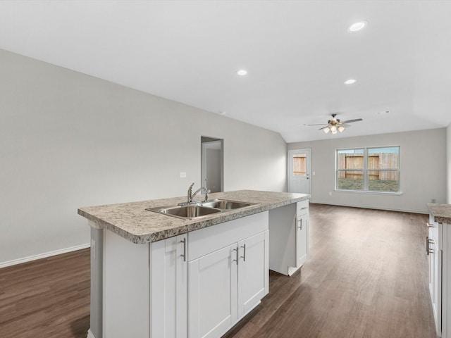 kitchen with a sink, white cabinetry, open floor plan, dark wood finished floors, and a center island with sink