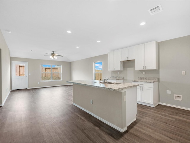 kitchen featuring plenty of natural light, a center island with sink, visible vents, and white cabinets