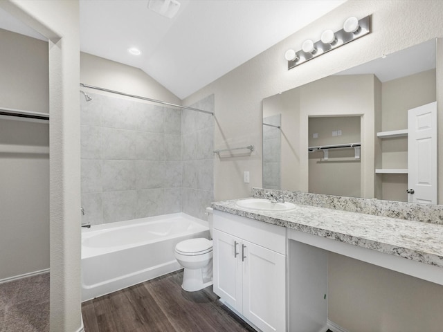 bathroom with lofted ceiling, toilet, tub / shower combination, vanity, and wood finished floors