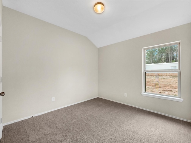 carpeted empty room with baseboards and vaulted ceiling