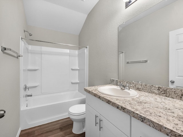 bathroom with toilet, wood finished floors, vanity, bathing tub / shower combination, and vaulted ceiling