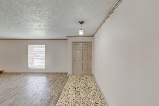 interior space featuring ornamental molding, light wood finished floors, a textured ceiling, and baseboards