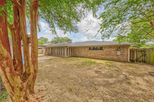 back of house featuring a patio area, brick siding, fence, and a chimney