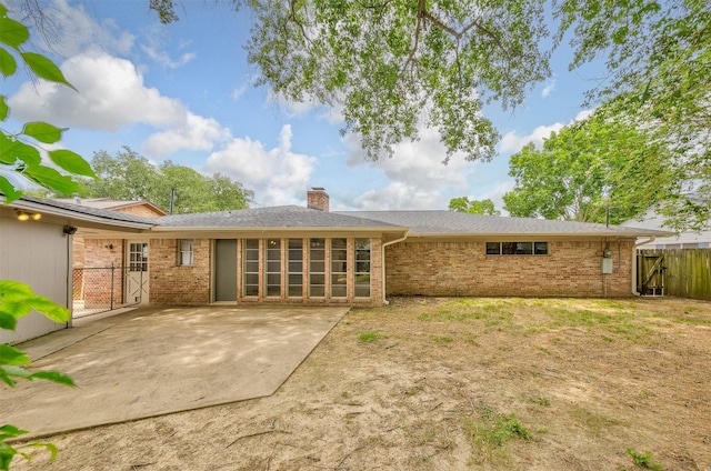 back of property with a patio area, a gate, a chimney, and brick siding