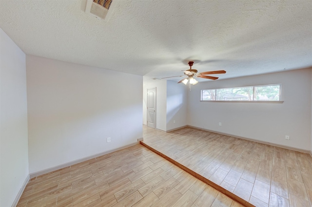 unfurnished room featuring visible vents, baseboards, ceiling fan, a textured ceiling, and light wood-style floors