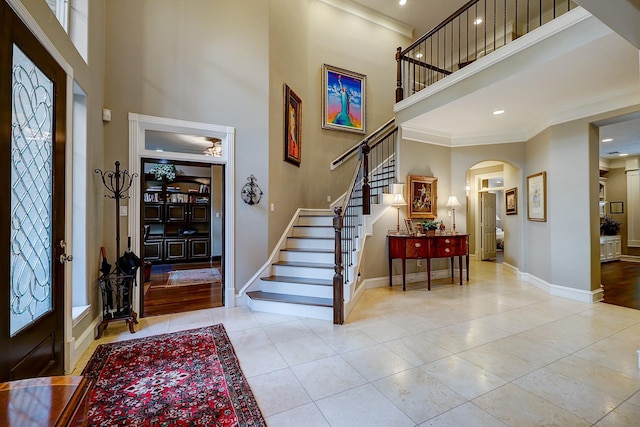 37314 Edgewater Dr, Pinehurst, TX 77362 - tiled entrance foyer with a high ceiling, arched walkways, baseboards, stairway, and crown molding