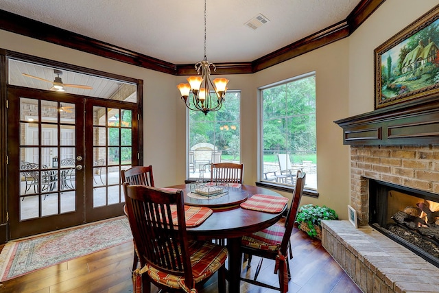 37314 Edgewater Dr, Pinehurst, TX 77362 - dining space featuring hardwood / wood-style flooring, french doors, crown molding, a chandelier, and a brick fireplace