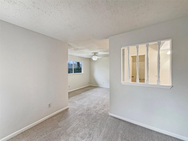 unfurnished room with carpet floors, a ceiling fan, baseboards, and a textured ceiling