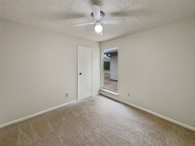 empty room with a textured ceiling, carpet floors, a ceiling fan, and baseboards