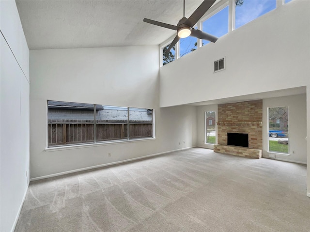 unfurnished living room featuring carpet, visible vents, a ceiling fan, a brick fireplace, and baseboards