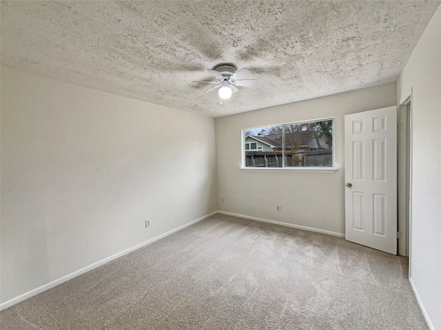 carpeted empty room featuring a textured ceiling, ceiling fan, and baseboards