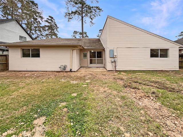 back of property featuring fence and a lawn