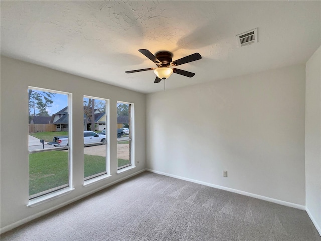 carpeted spare room featuring a textured ceiling, a ceiling fan, visible vents, and baseboards