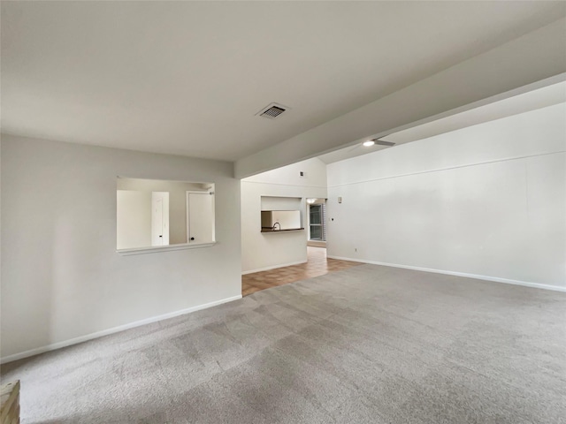 unfurnished living room featuring carpet floors, visible vents, and baseboards