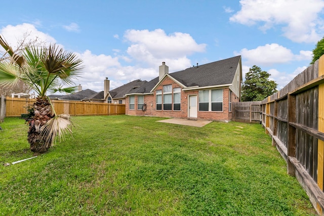 rear view of house featuring a fenced backyard, brick siding, a lawn, a chimney, and a patio area