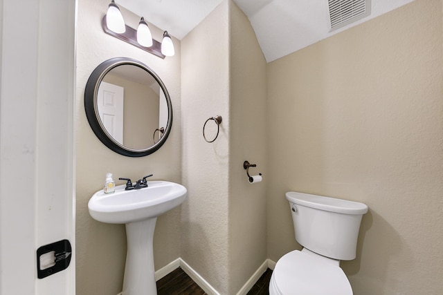 half bathroom with toilet, visible vents, and baseboards