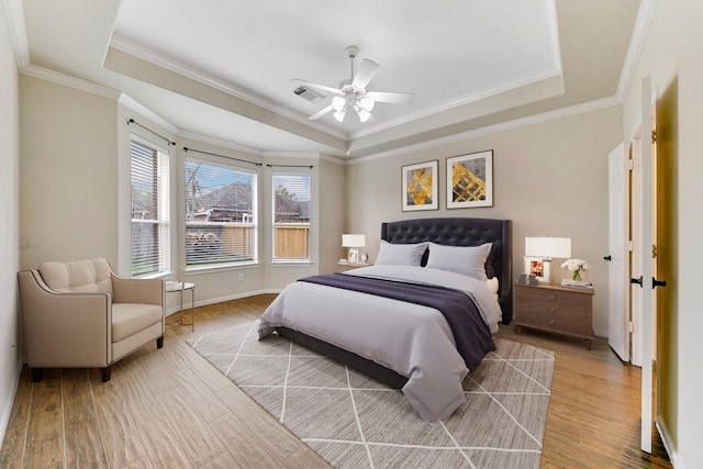 bedroom with a raised ceiling, visible vents, light wood-style flooring, and baseboards