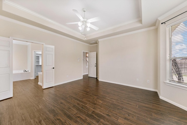 empty room featuring ornamental molding, wood finished floors, a raised ceiling, and baseboards