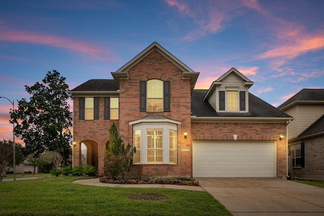 traditional-style home featuring driveway, a yard, a garage, and brick siding