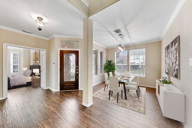 foyer featuring ornamental molding, visible vents, and wood finished floors