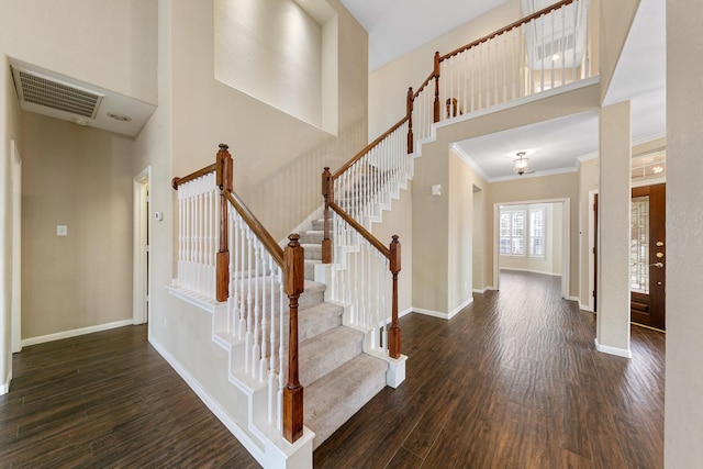 foyer featuring dark wood-type flooring, visible vents, a towering ceiling, and baseboards